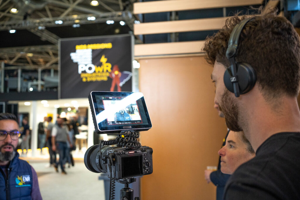 Théo Belnou filmando una entrevista con monitor externo y auriculares durante la producción de un documental en España.