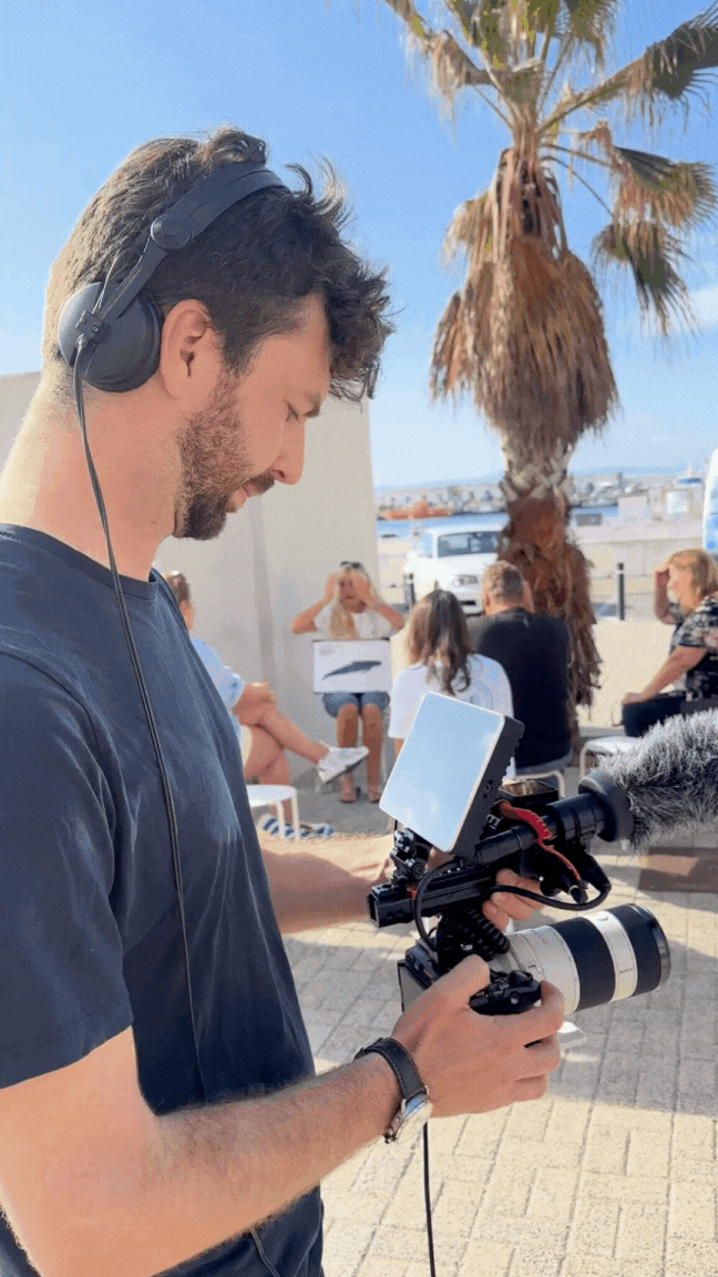 Théo Belnou filmando en exteriores con cámara y micrófono durante la creación de un vídeo para redes sociales.