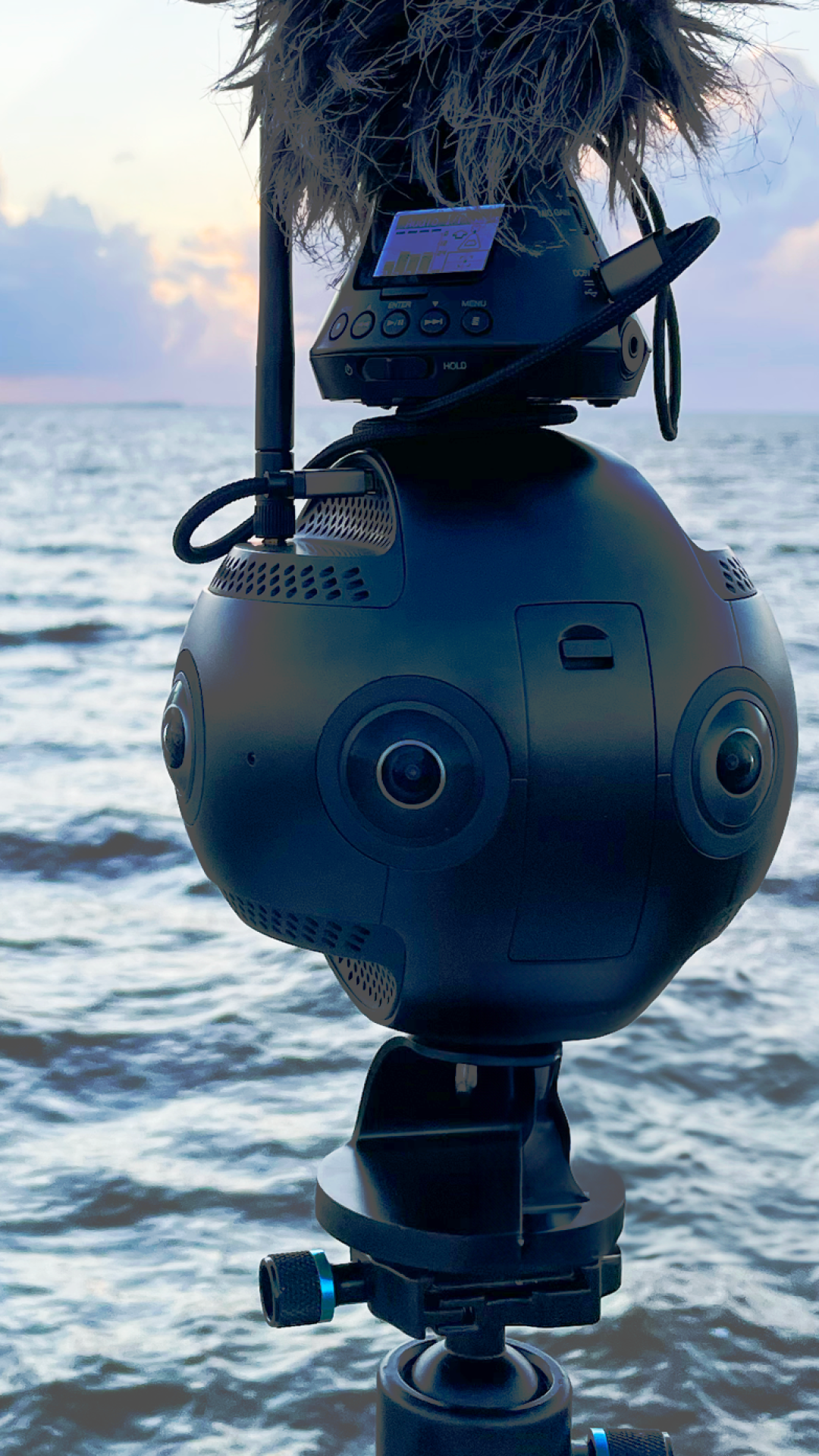 Insta 360 pro 2 camera with a microphone on top in front of the ocean with sunset.