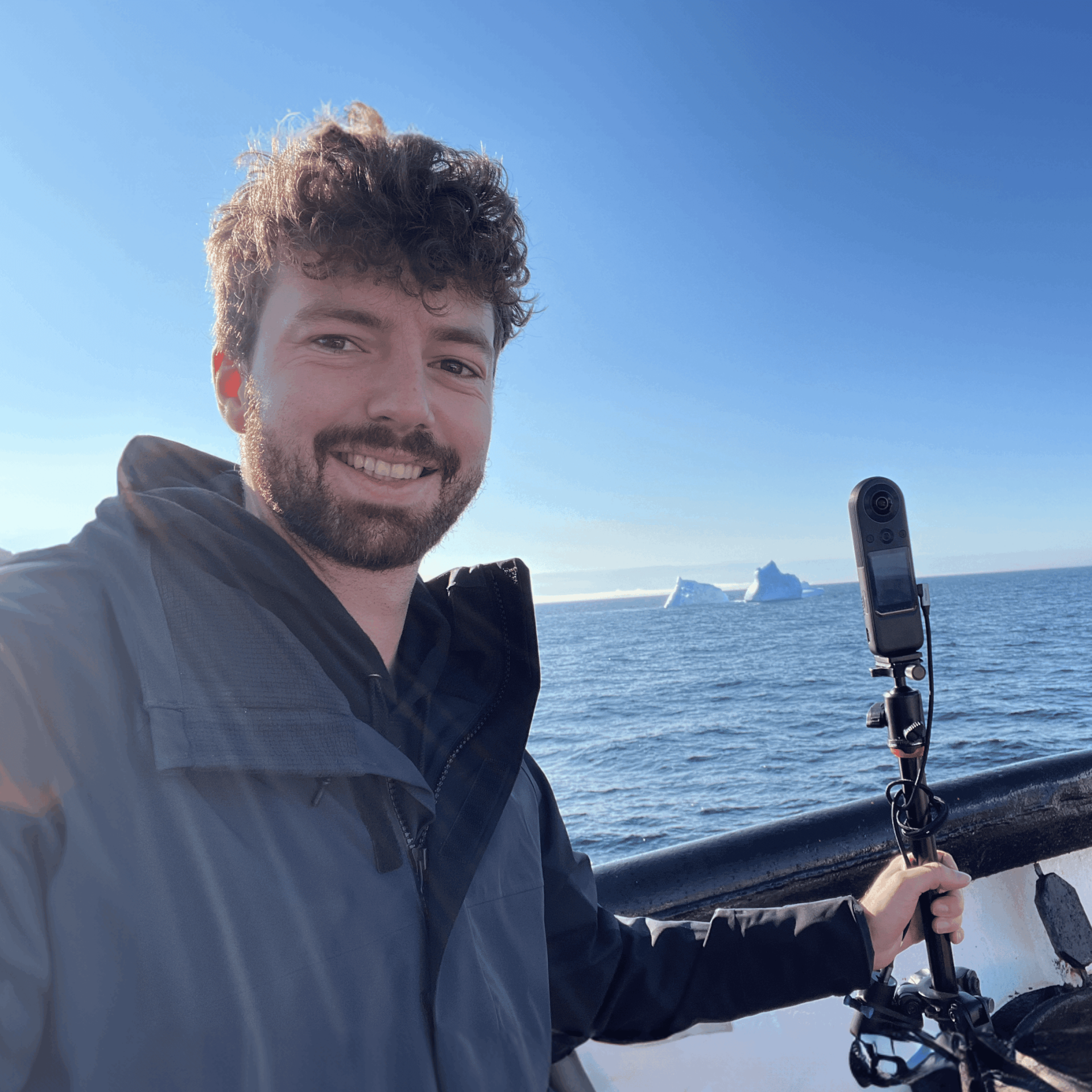 Théo Belnou realizando una captura de vídeo 360° en un barco frente a icebergs durante una expedición en el Ártico.