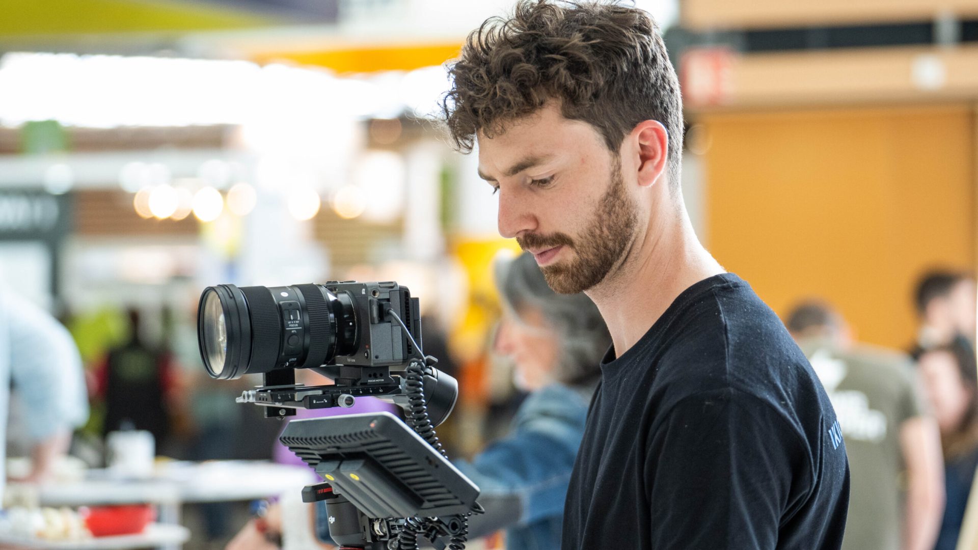 Théo Belnou, videógrafo especializado en video de eventos, realizando la grabación de un evento con cámara profesional.